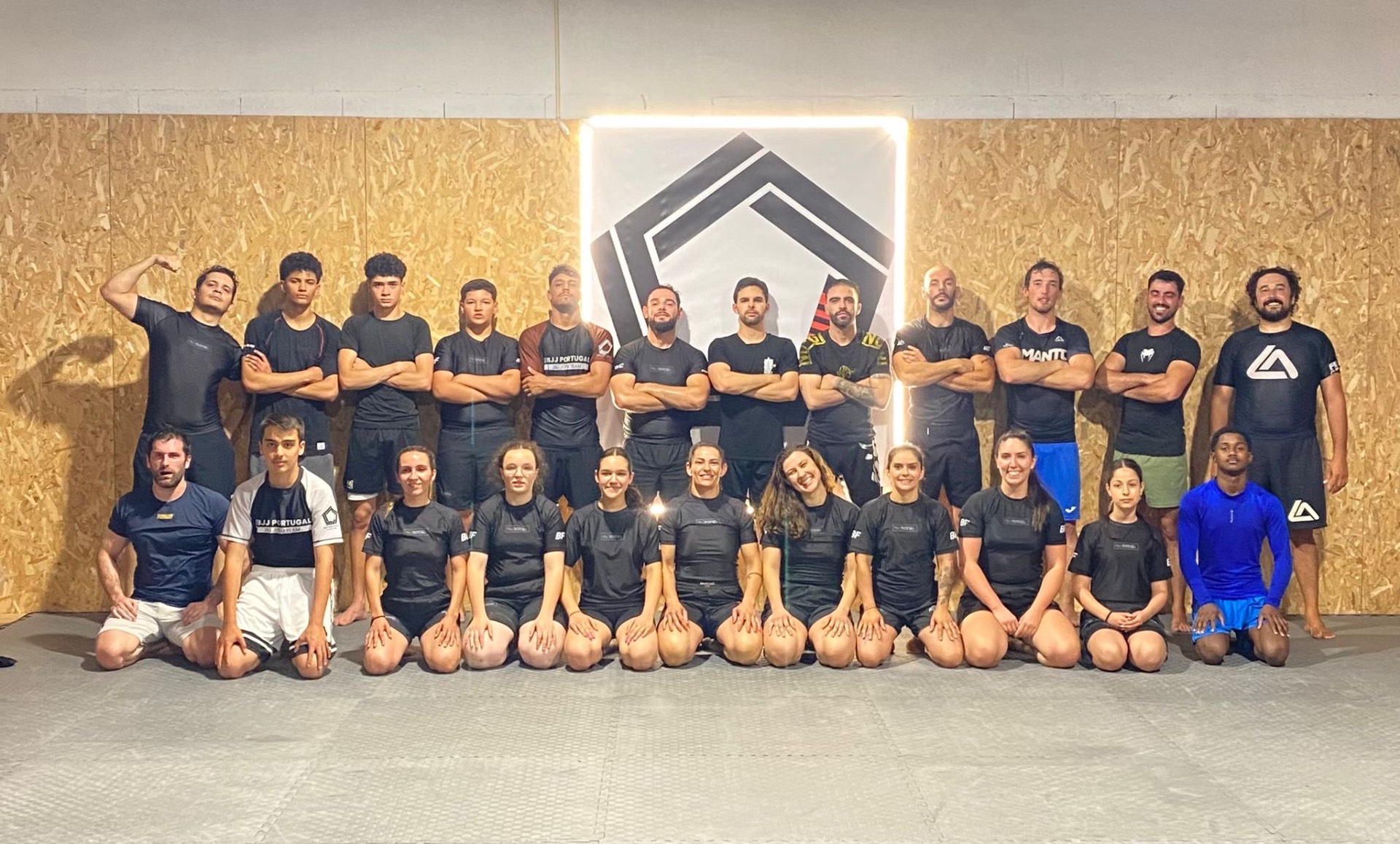 Comunidade EBJJ Portugal posando junto ao logótipo da escola