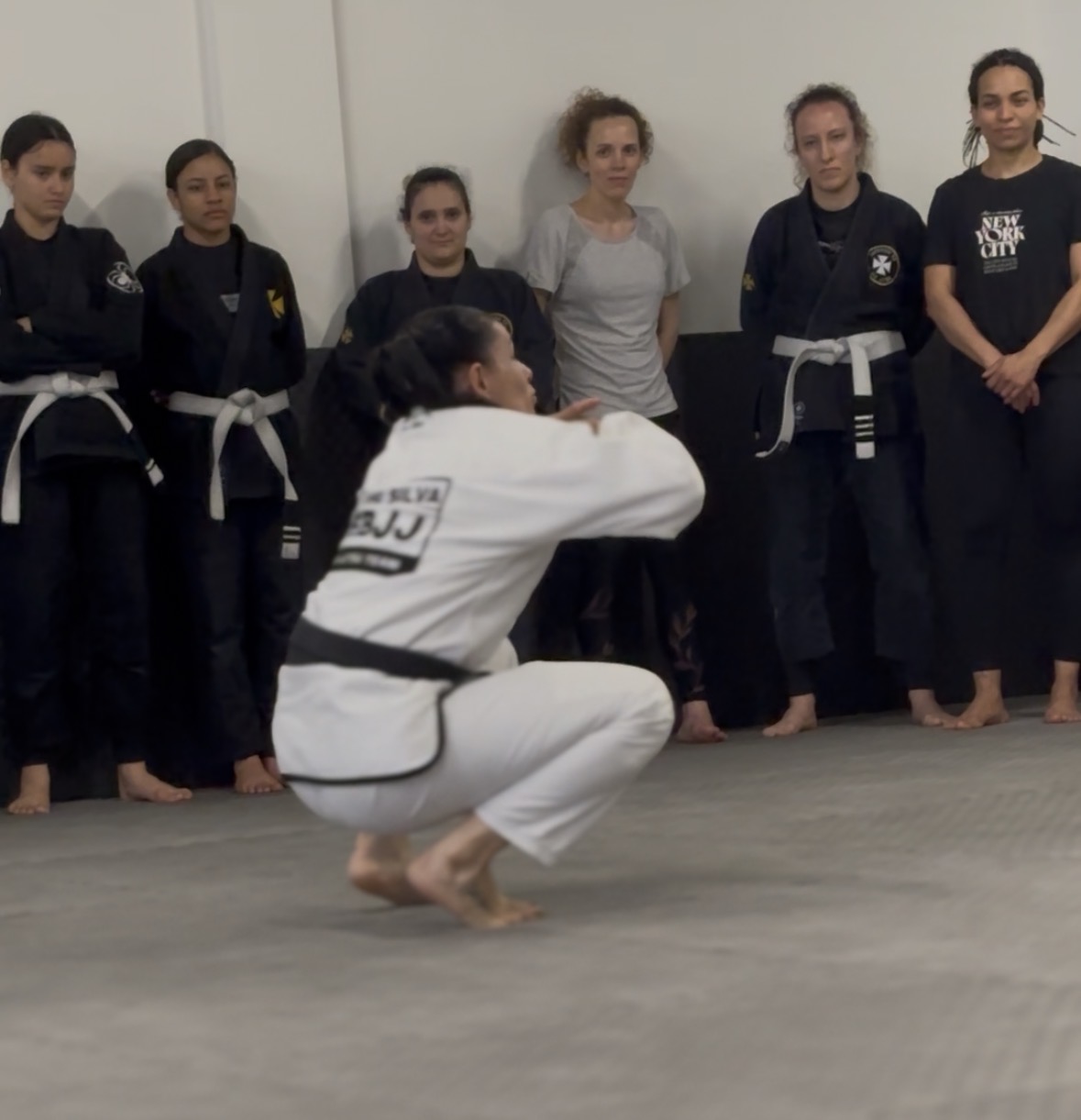 Aula de Jiu-Jitsu feminino — alunas a observarem a professora